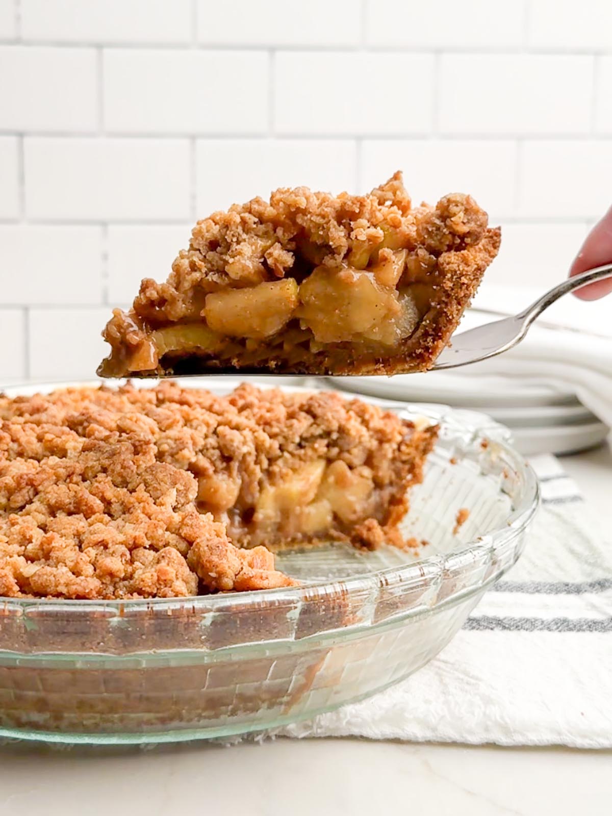 hand holding pie server with a piece of apple pie with graham cracker crust.