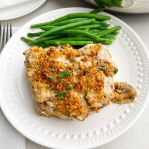 baked pork chops with cream of mushroom soup on a white plate with green beans
