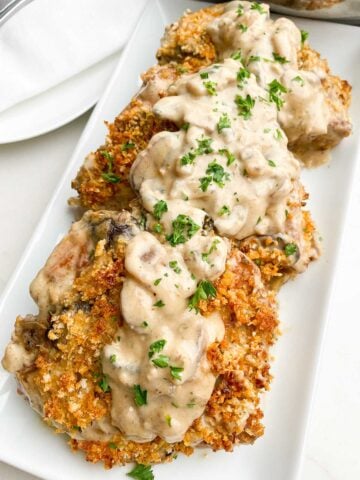 baked pork chops with cream of mushroom soup on a white platter topped with mushroom gravy.