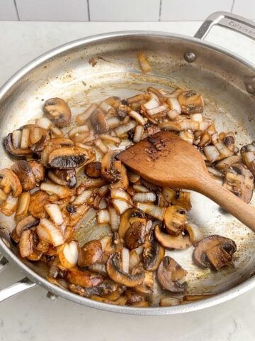 sauteed mushrooms and onions in stainless steel skillet.
