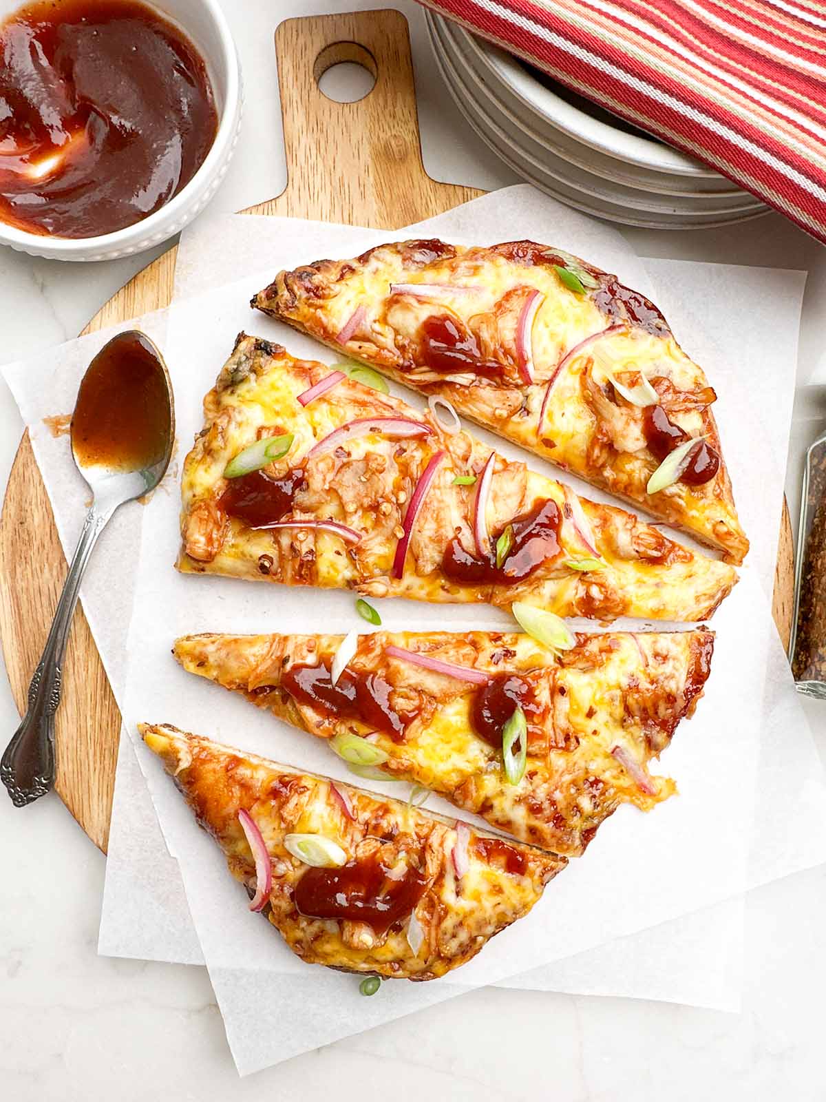 bbq chicken flatbread cut into slices on parchment covered wooden cutting board