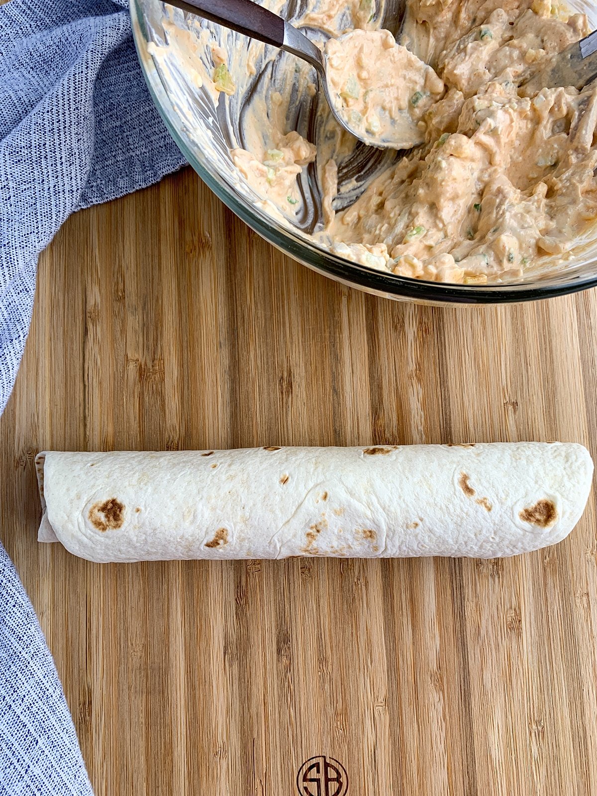 Buffalo Chicken Pinwheel tortilla rolled up on a wooden cutting board