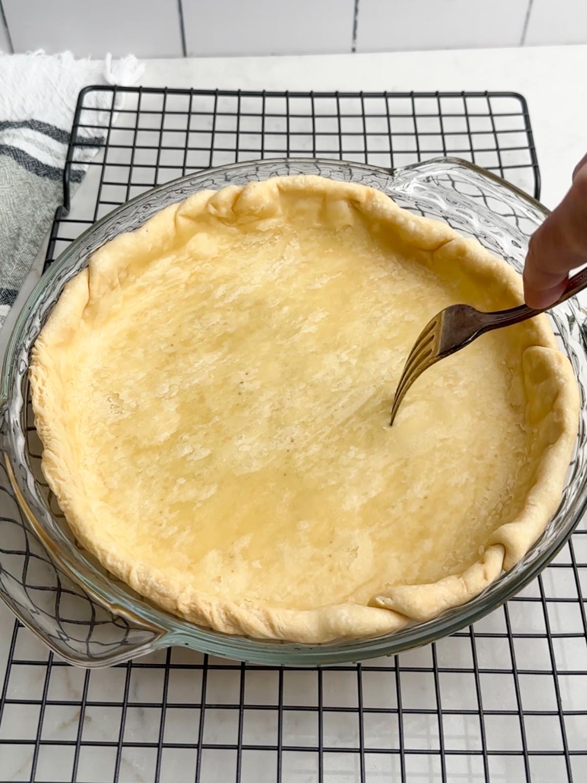 Fork poking holes in pie crust.