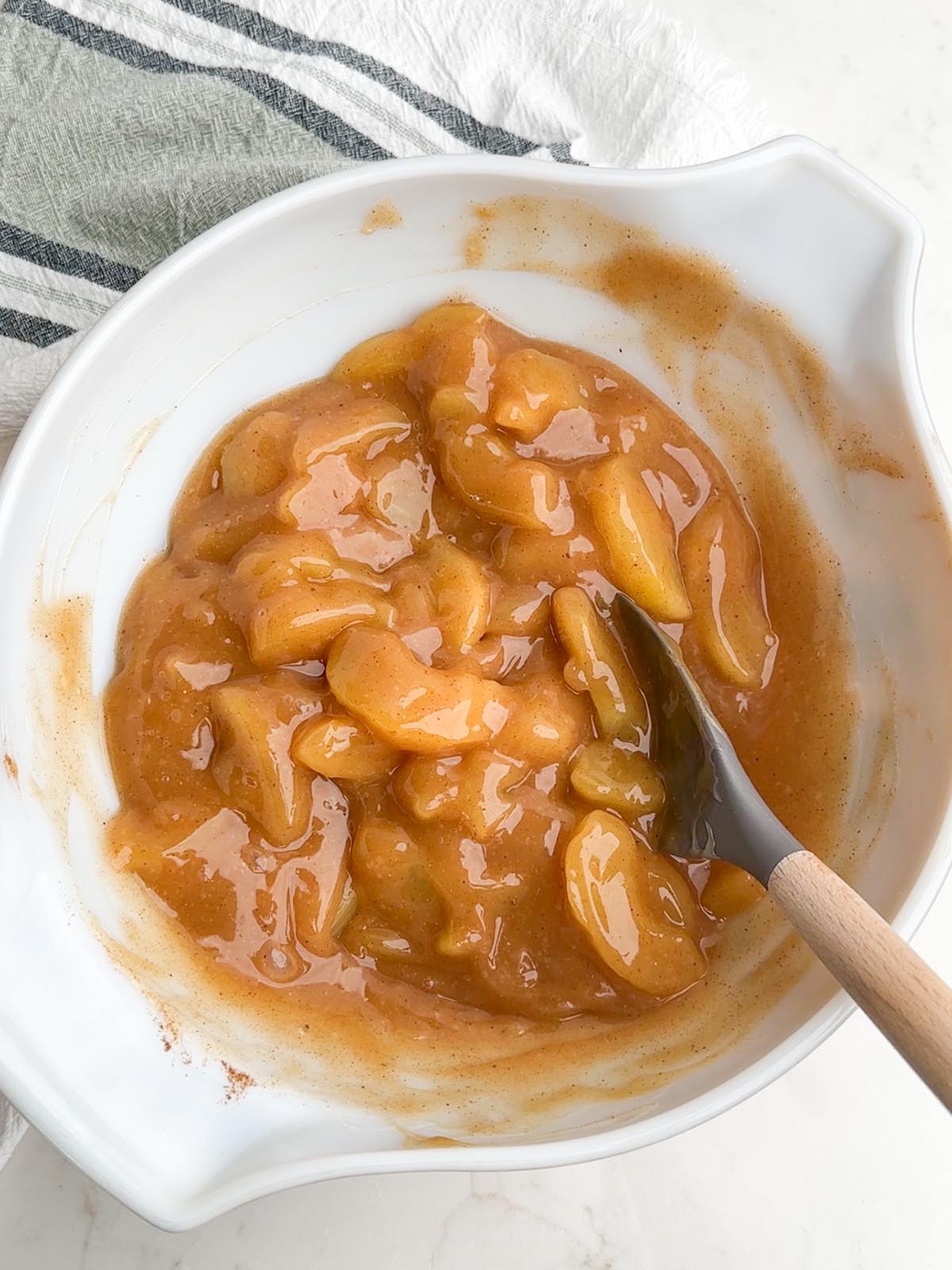 Apple pie filling in a white mixing bowl.