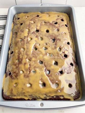 chocolate cake with holes on top drizzled with caramel sauce.