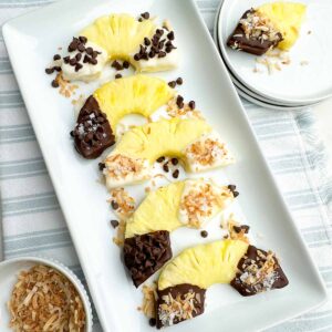 chocolate covered pineapple half rings on a white platter