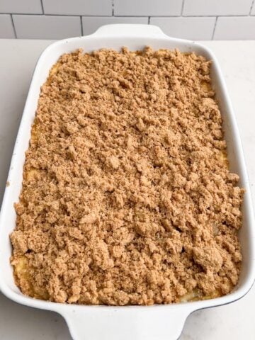 cinnamon streusel topping over the apple pie filling in a white baking dish.