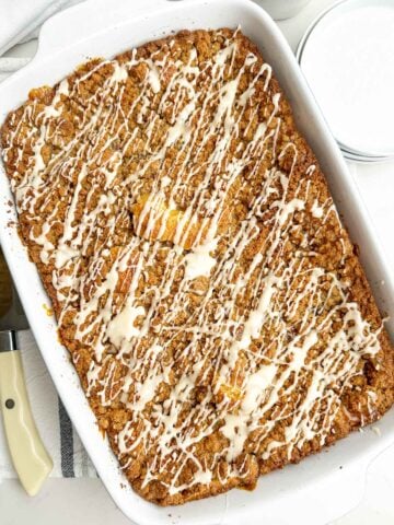 coffee cake with icing drizzle on a white baking dish.