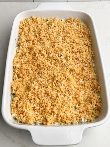 unbaked crab spinach artichoke dip in white baking dish.