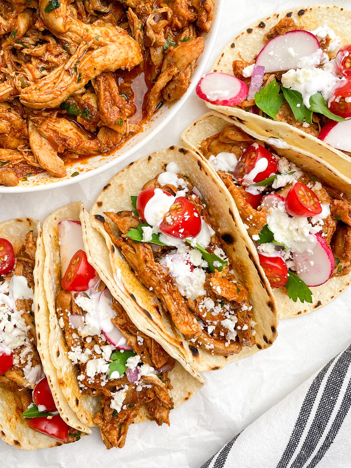 crock pot chicken tacos next to a bowl of shredded salsa chicken