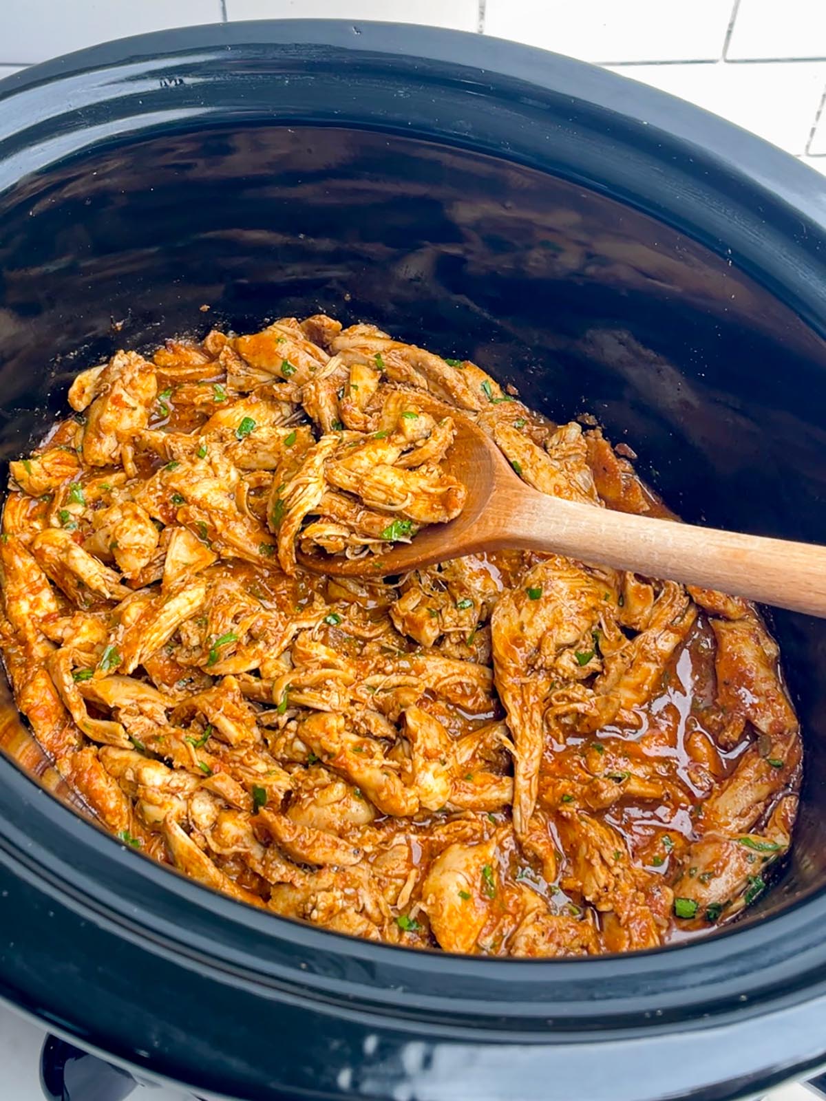 shredded salsa chicken in a black slow cooker