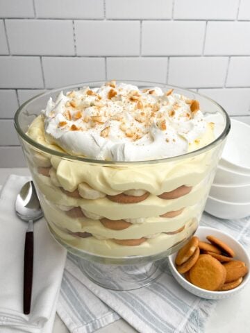 easy banana pudding in a trifle dish on a blue and white napkin.