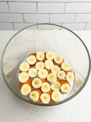 nilla wafers and bananas layered in a trifle bowl.