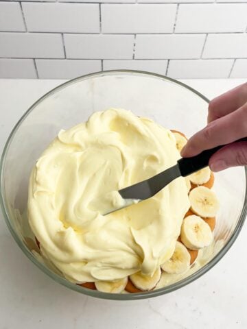 hand spreading pudding mixture into trifle dish.