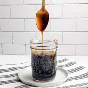 spoon drizzling honey teriyaki sauce into a mason jar of sauce