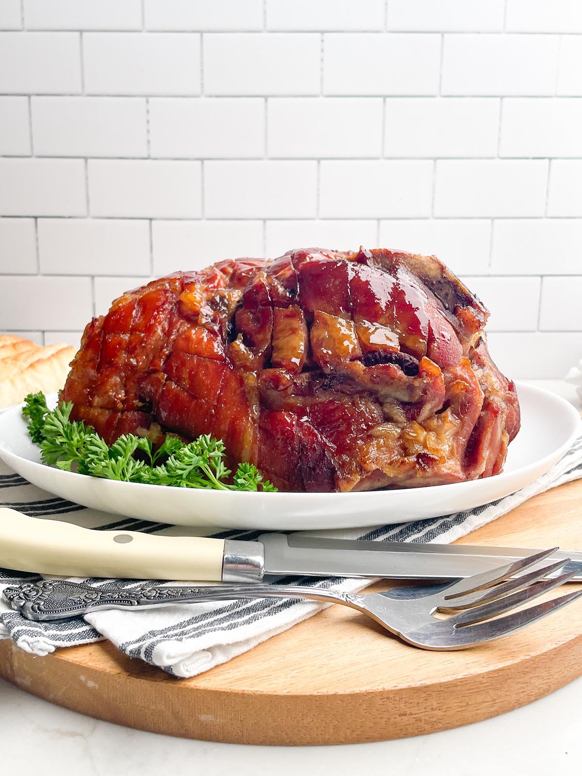 glazed roaster oven ham on a white platter.