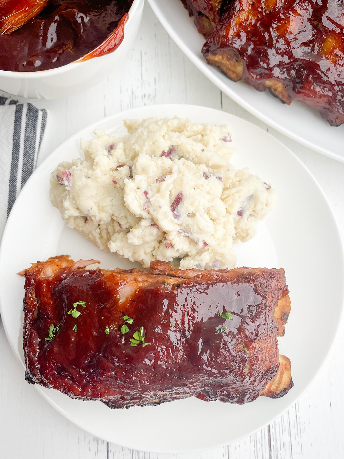 roaster oven BBQ ribs on a white plate with red skin mashed potatoes