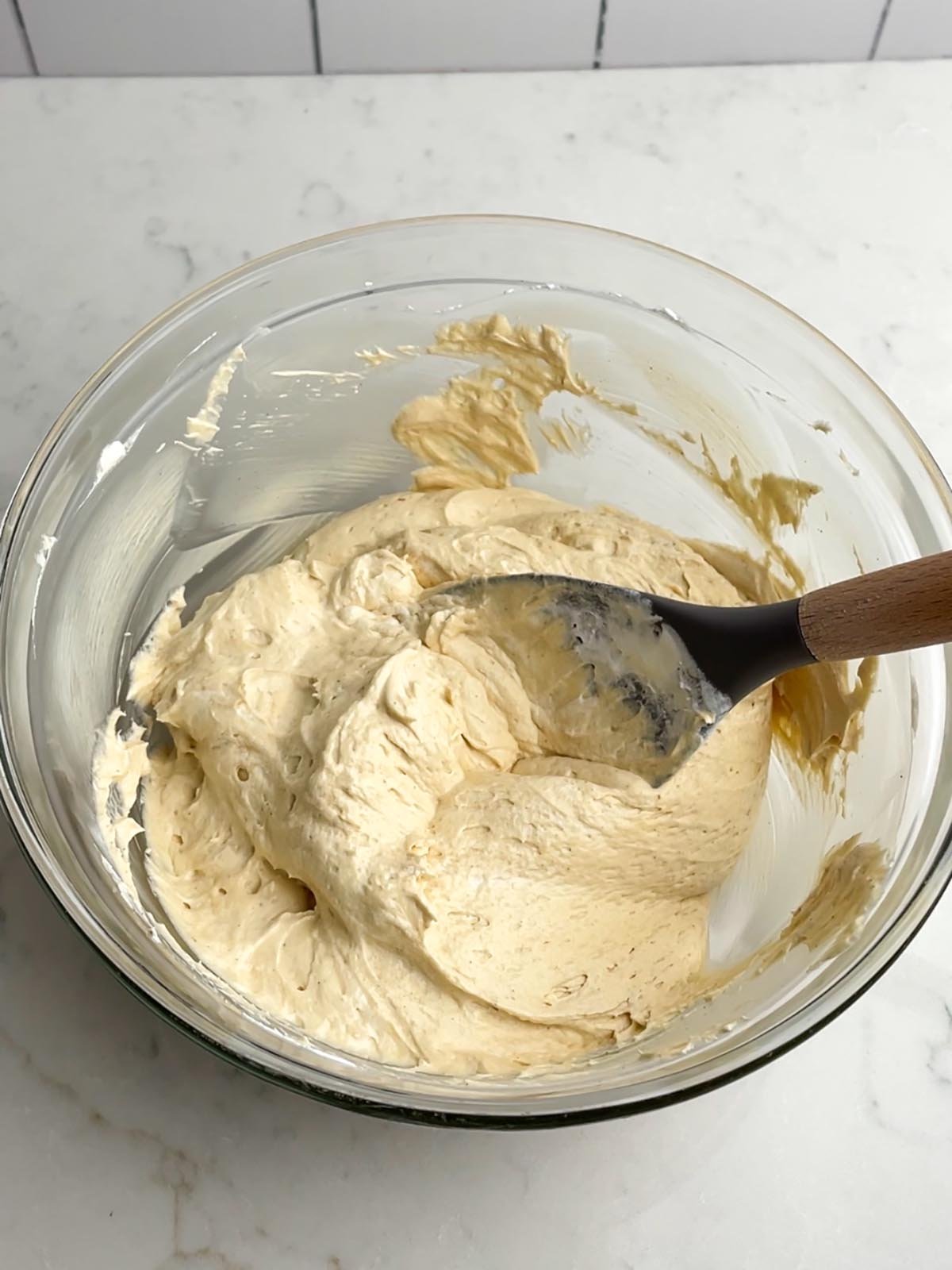 caramel apple dip mixture in a clear bowl with a spatula