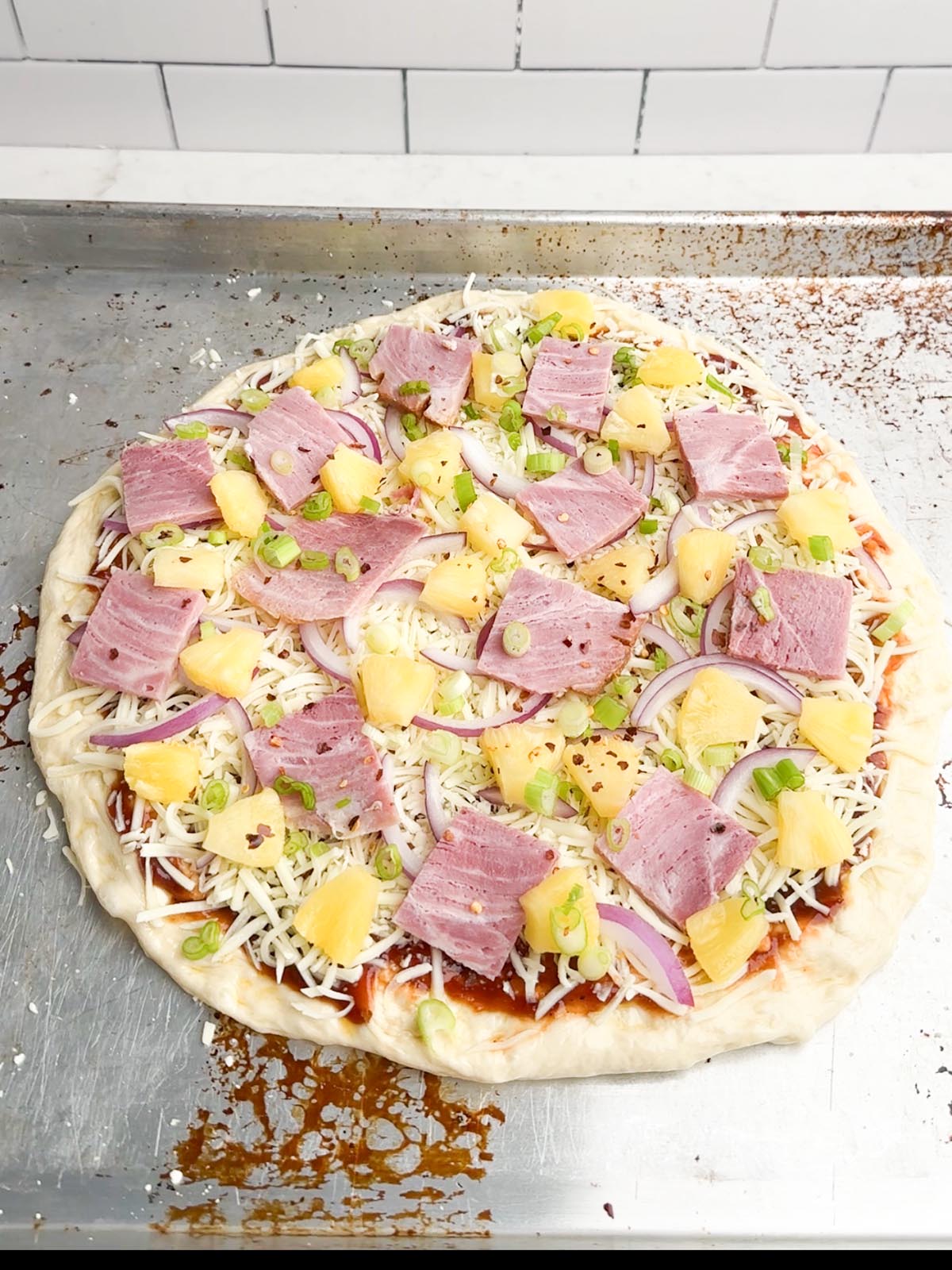 assembled pineapple pizza on baking sheet