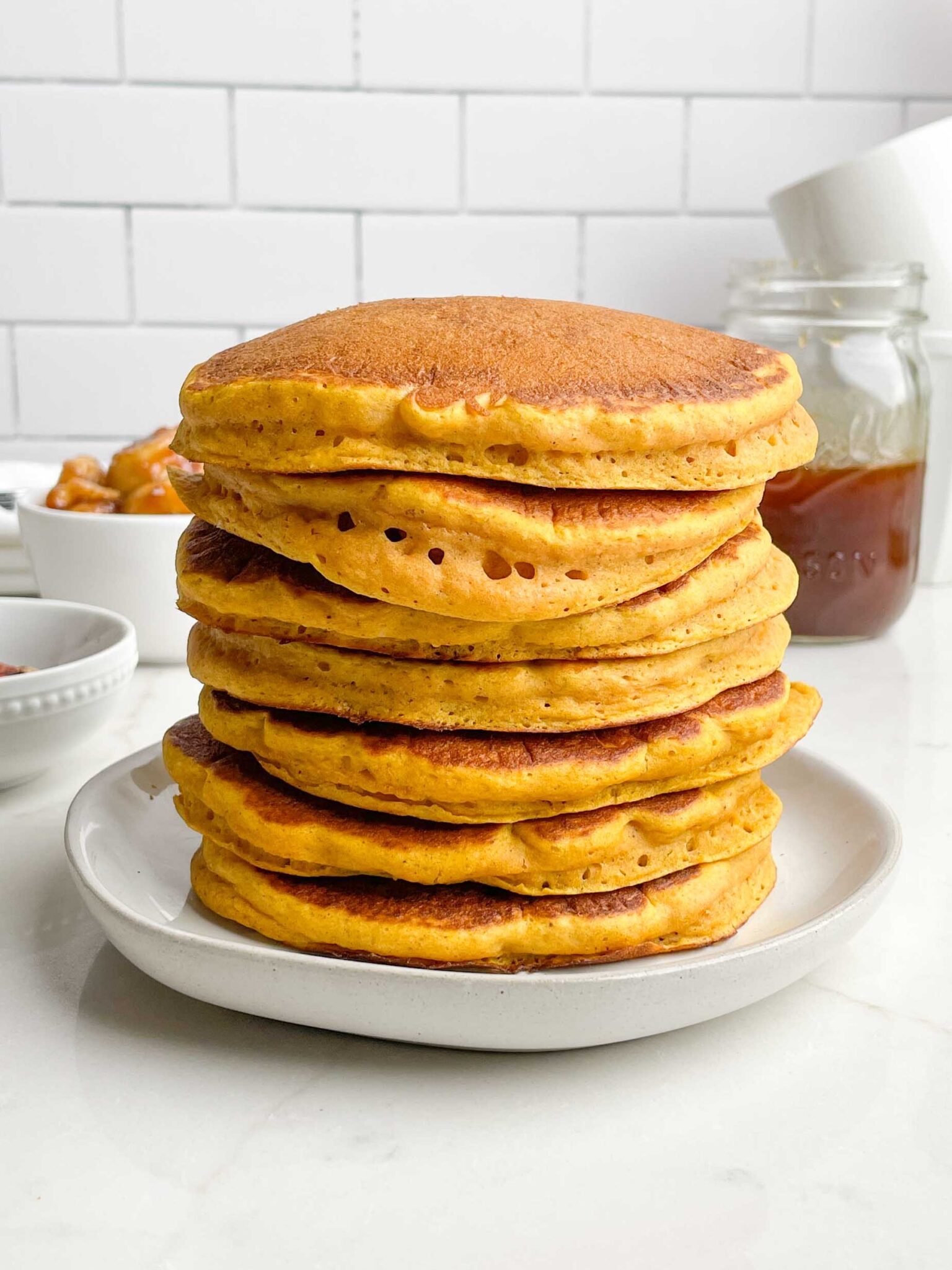 stack of pumpkin pancakes on a white plate.