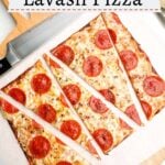 pepperoni lavash pizza cut into triangles on parchment on a wooden cutting board