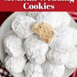 Mexican Christmas cookies on a white plate next to a holiday mug and bowl of pine cones