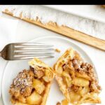 mini puff pastry apple pie cut in half on a white plate