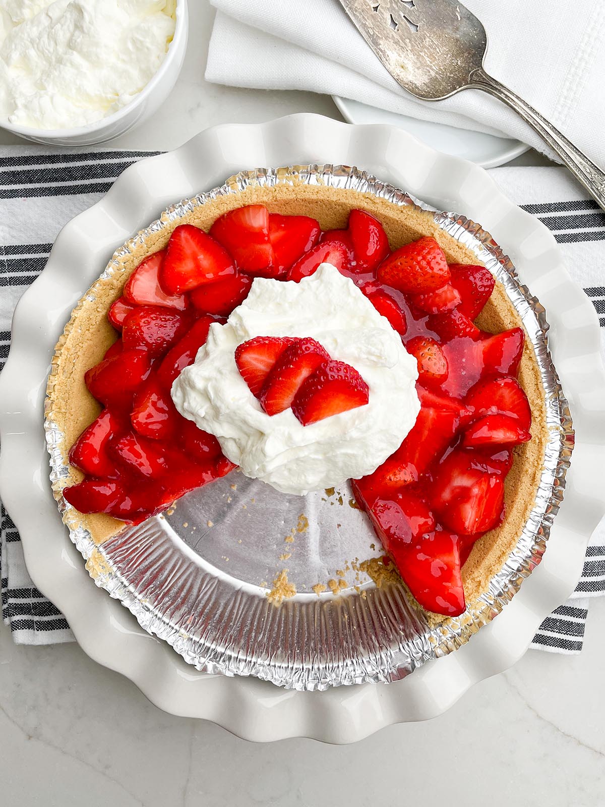 strawberry jello pie in white pie plate with whipped cream.