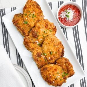 air fryer panko boneless chicken thighs on a white platter next to a bowl of marinara