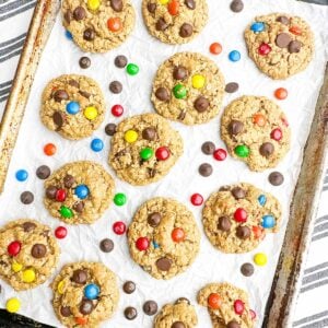 Monster cookies on parchment paper on a baking pan.