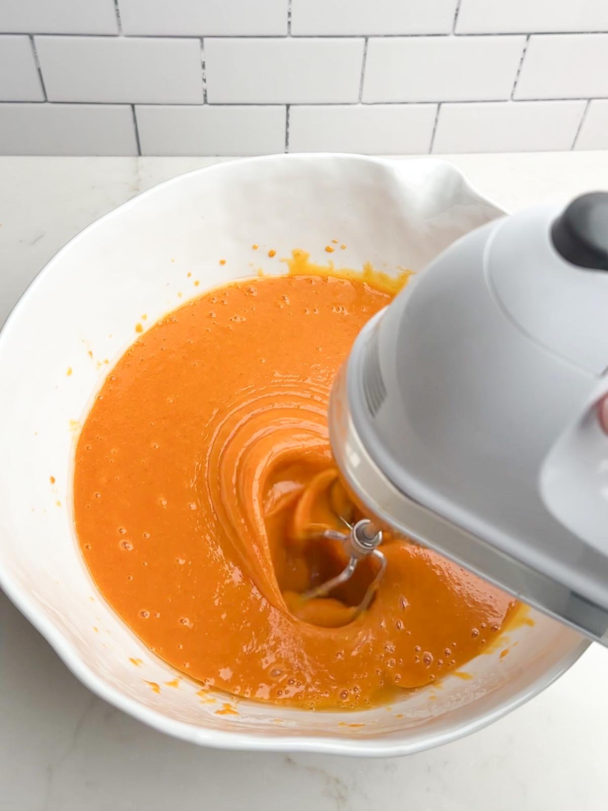 hand mixer mixing pumpkin bars batter in white bowl