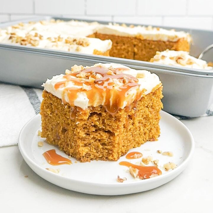 pumpkin pie bar with cream cheese frosting, walnuts, and caramel sauce on a white plate
