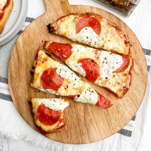 baked pepperoni flatbread cut into slices on a wooden cutting board