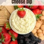 pineapple cream cheese dip in a white bowl on a wooden cutting board with fruit, graham crackers, and cookies