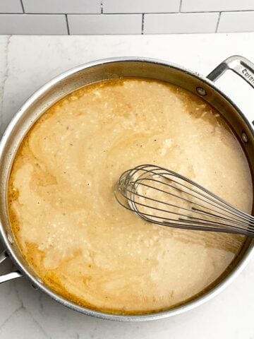Gravy mixture in large skillet with a whisk.