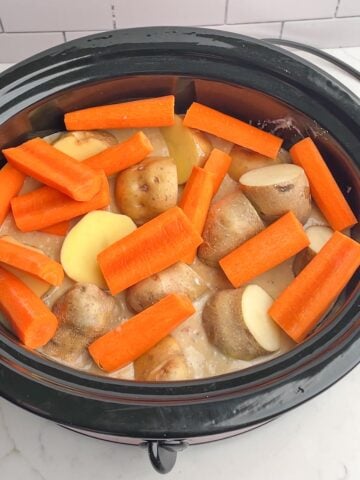 Pot roast with onion soup mix, carrots, and potatoes in crock pot.