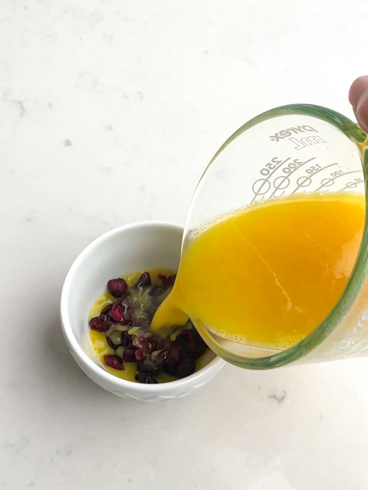 pouring orange juice over dried cranberries