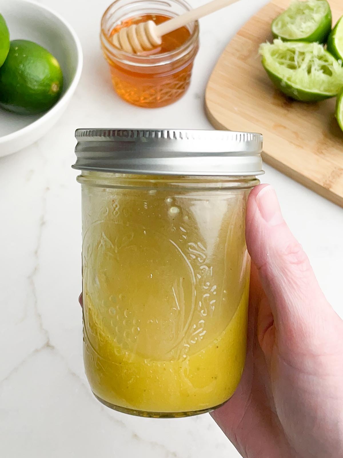 hand holding mason jar with honey lime dressing