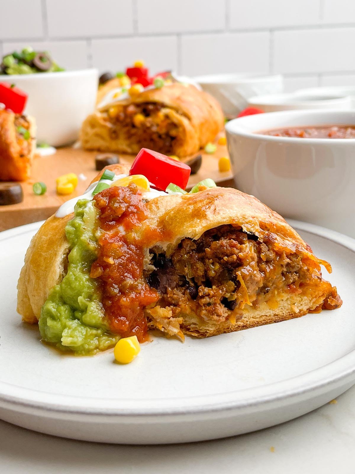 slice of taco ring on a white plate with taco ring in background