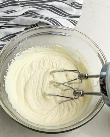 clear bowl with whipped ricotta with beaters in the bowl.