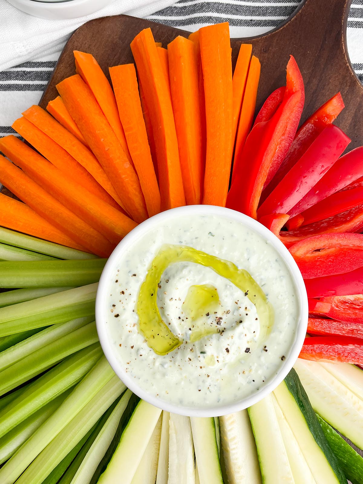 yogurt feta dip in a white bowl surrounded by vegetables